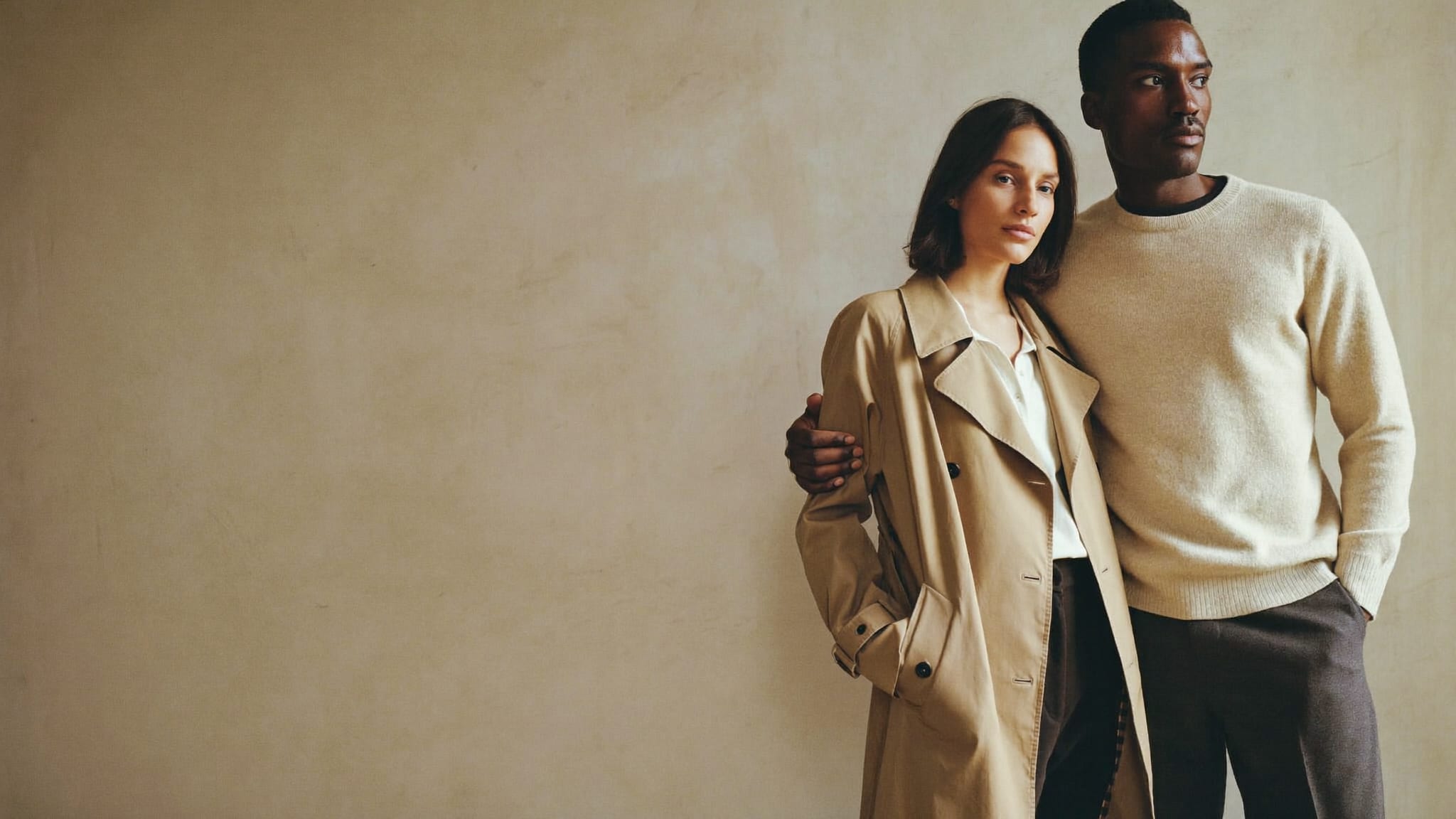Two models in a camel trench coat and an oatmeal knit jumper